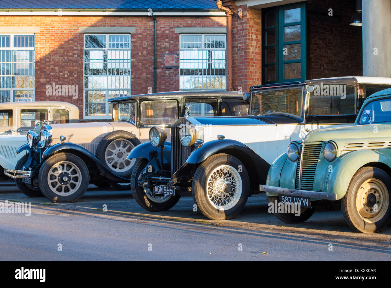 Line of Vintage cars including a 1933 Rolls Royce  outside a garage at Bicester Heritage centre. Bicester, Oxfordshire, England. Stock Photo