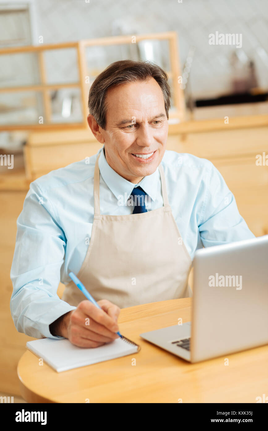 Busy satisfied man sitting and making notices. Stock Photo