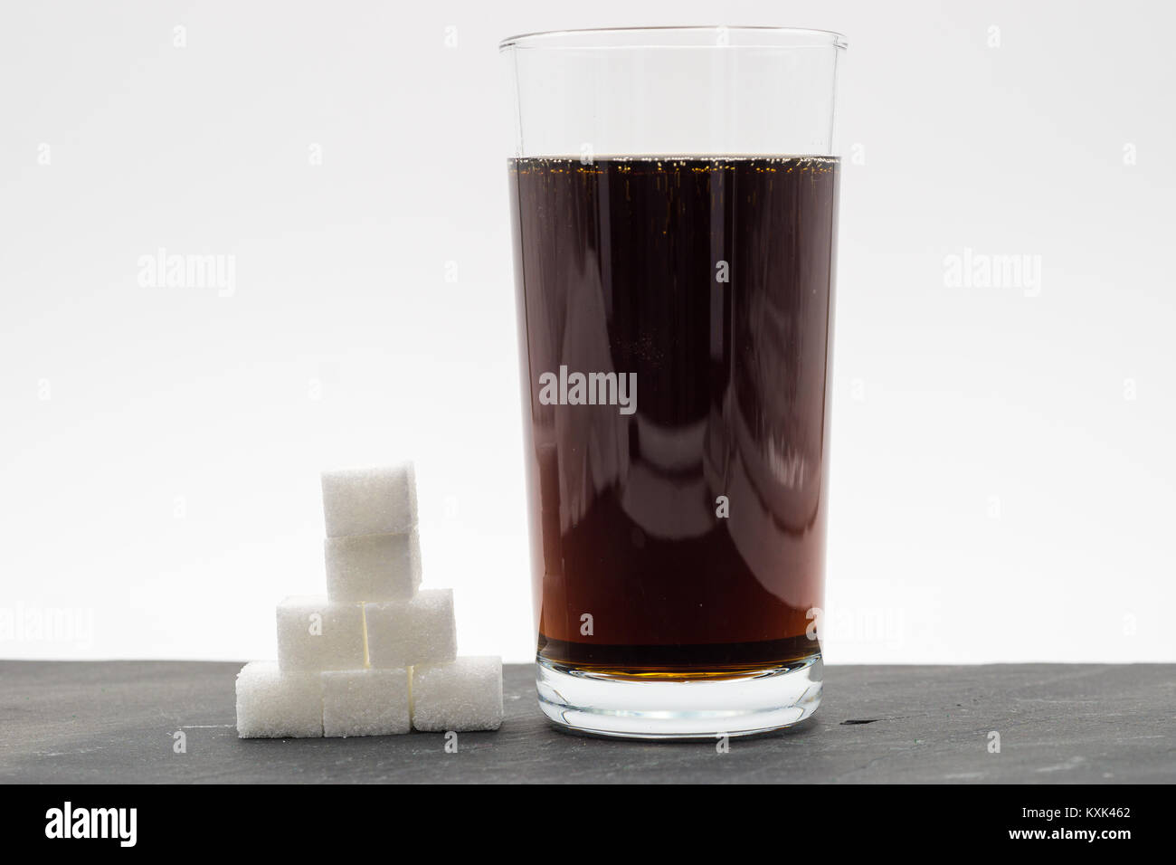 Glass full of soft drink, next to it is the amount of sugar used in it Stock Photo