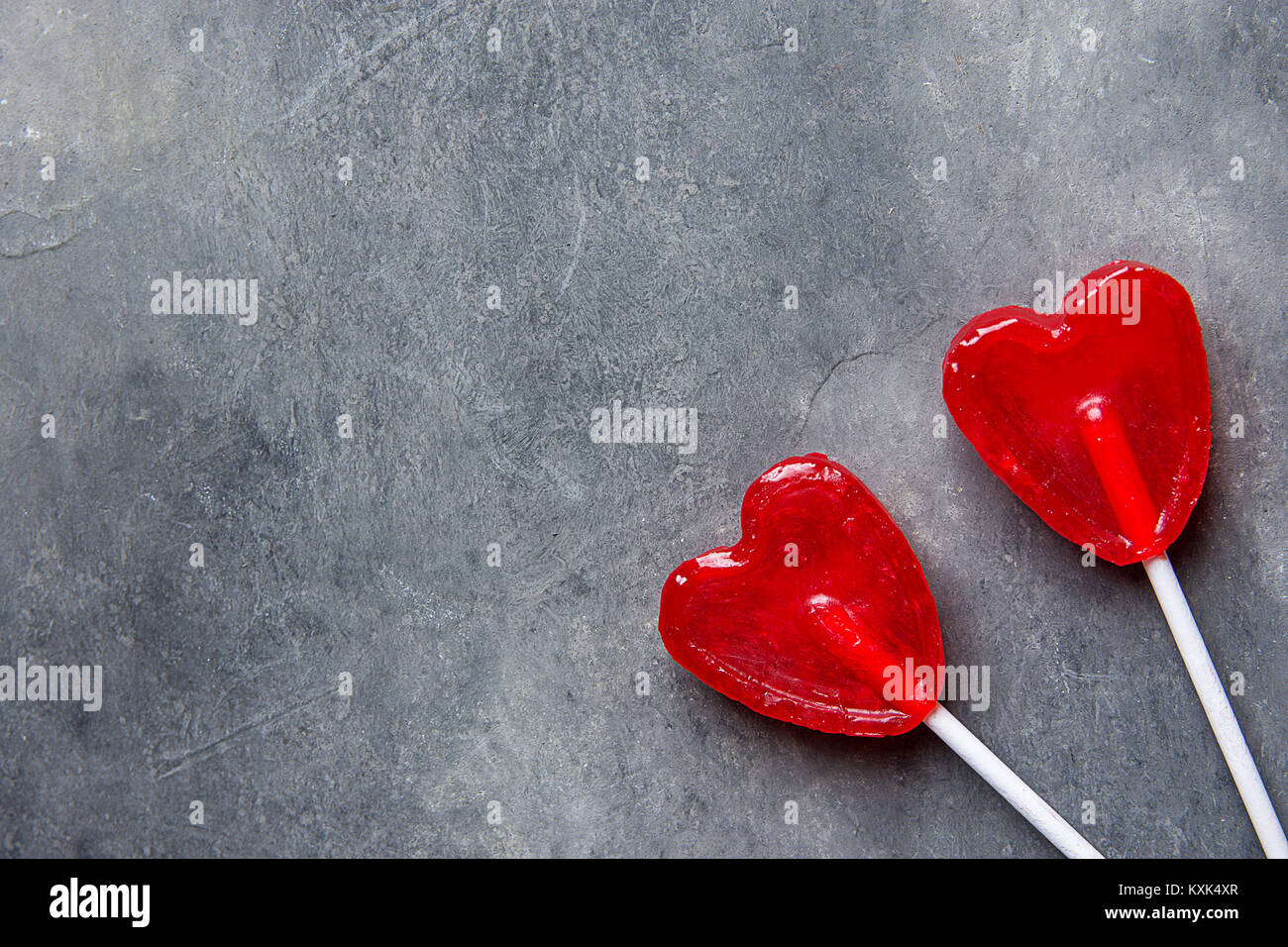 Two Red Heart Shape Candy Lollipops on Sticks on Dark Stone Background. Valentine Romantic Love Greeting Card Banner Poster with Copy Space. Creative  Stock Photo