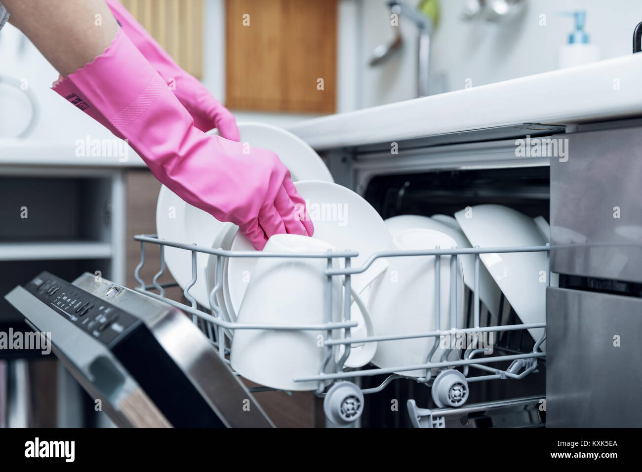 housewife taking out clean dishware from dishwasher at home kitchen Stock Photo