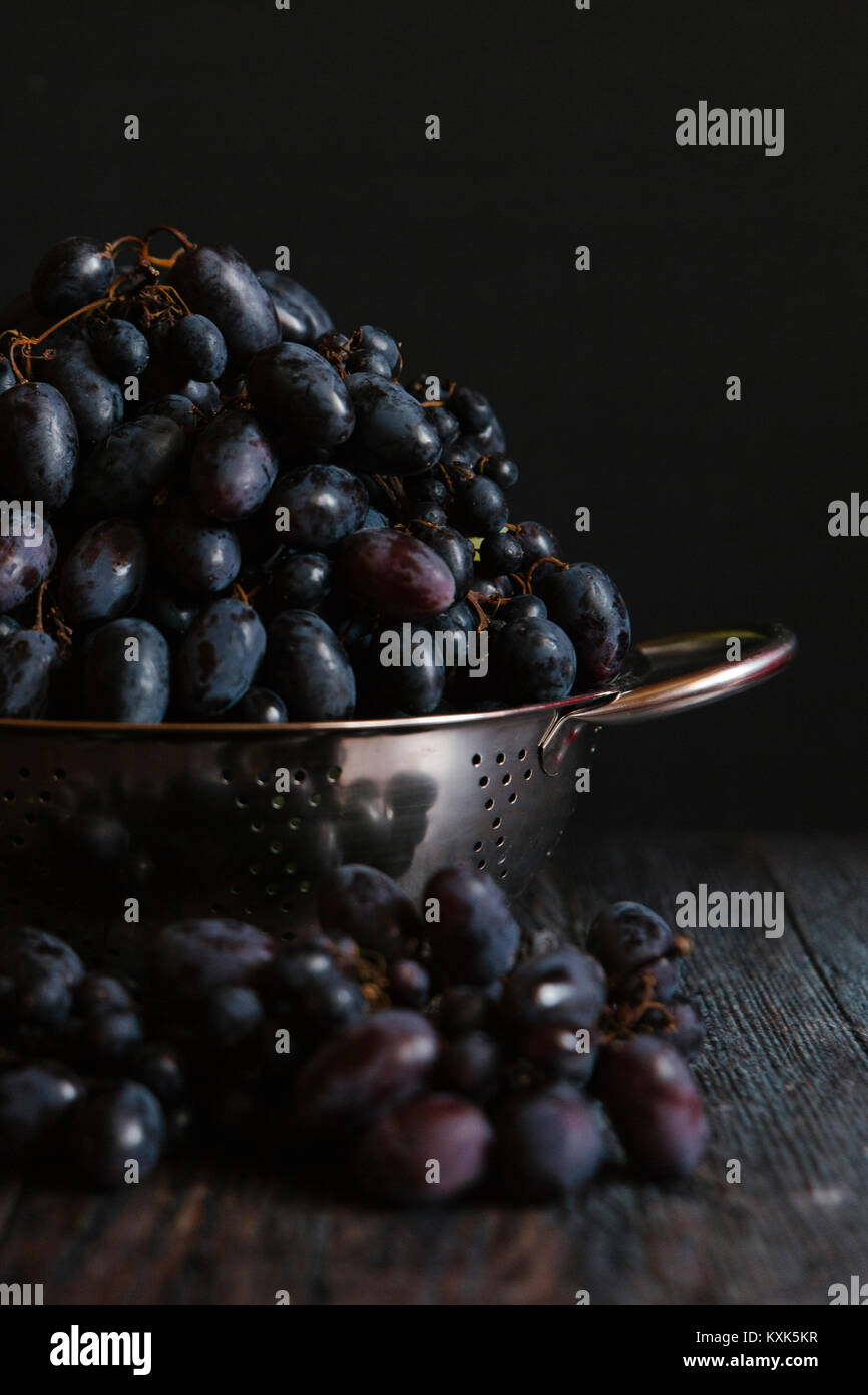 Close-up of grapes in colander on table against black background Stock Photo