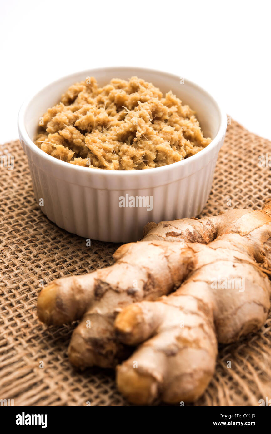 Fresh mashed Ginger / Ginger paste in white bowl with raw ginger over white background Stock Photo