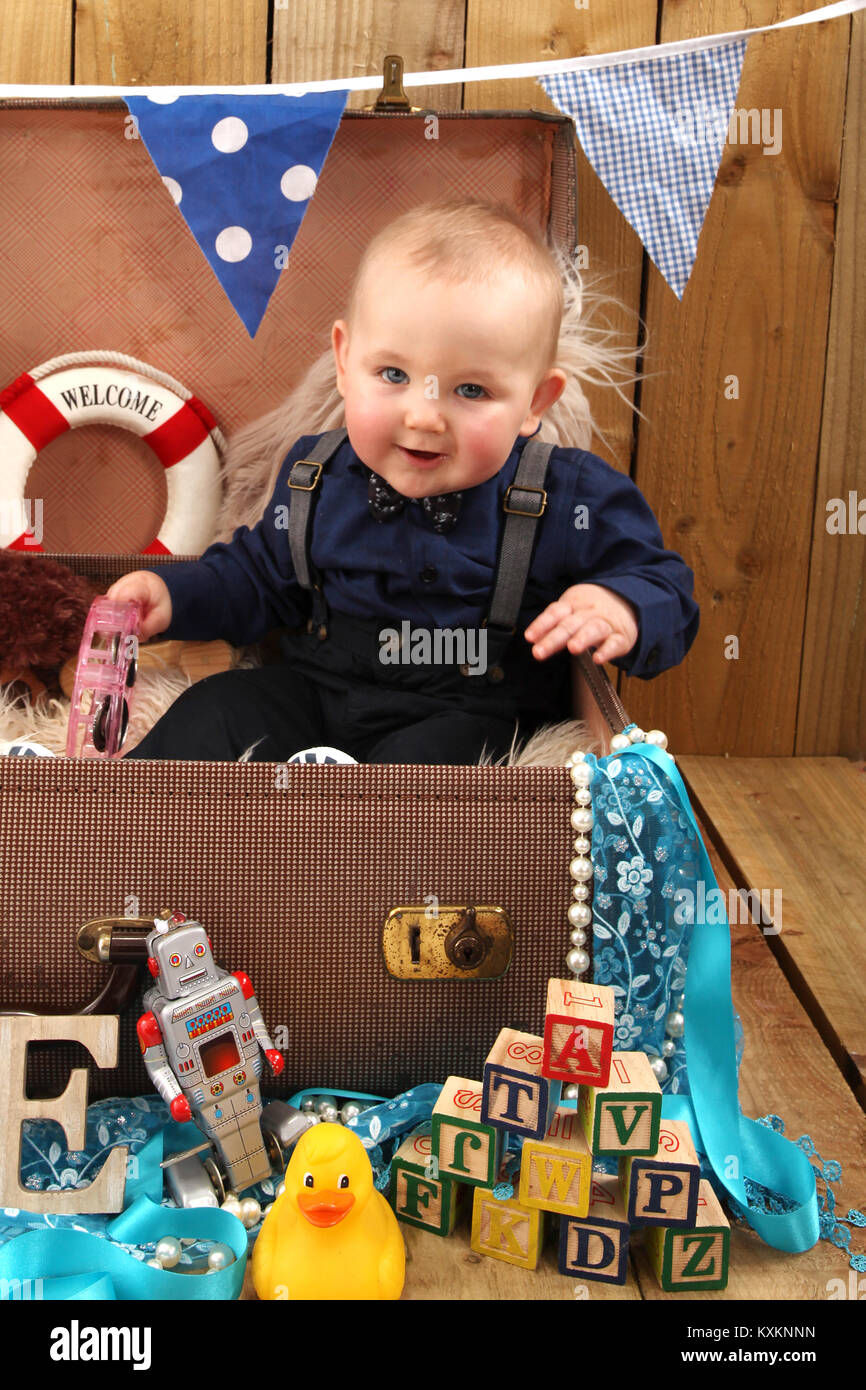 baby boy sitting in suitcase playing with toys, play time Stock Photo