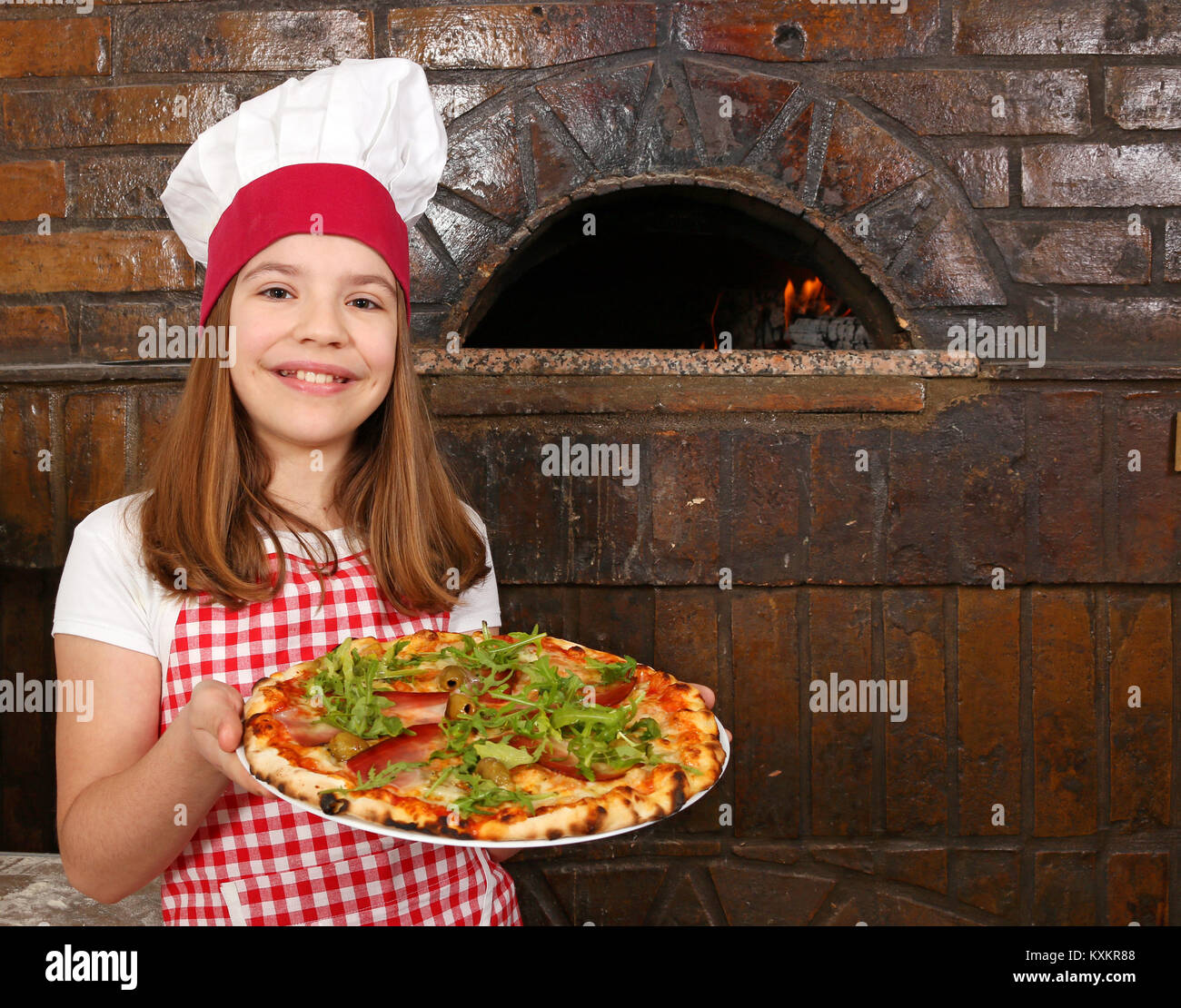 happy little girl cook with pizza in pizzeria Stock Photo