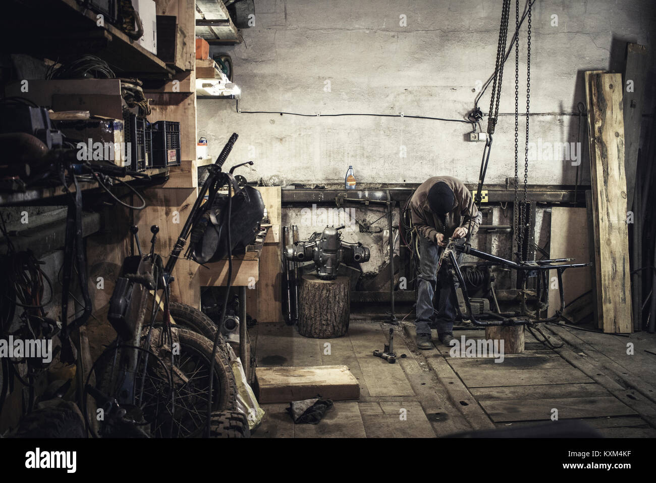 Mechanic repairing dismantled vintage motorcycle in workshop Stock Photo