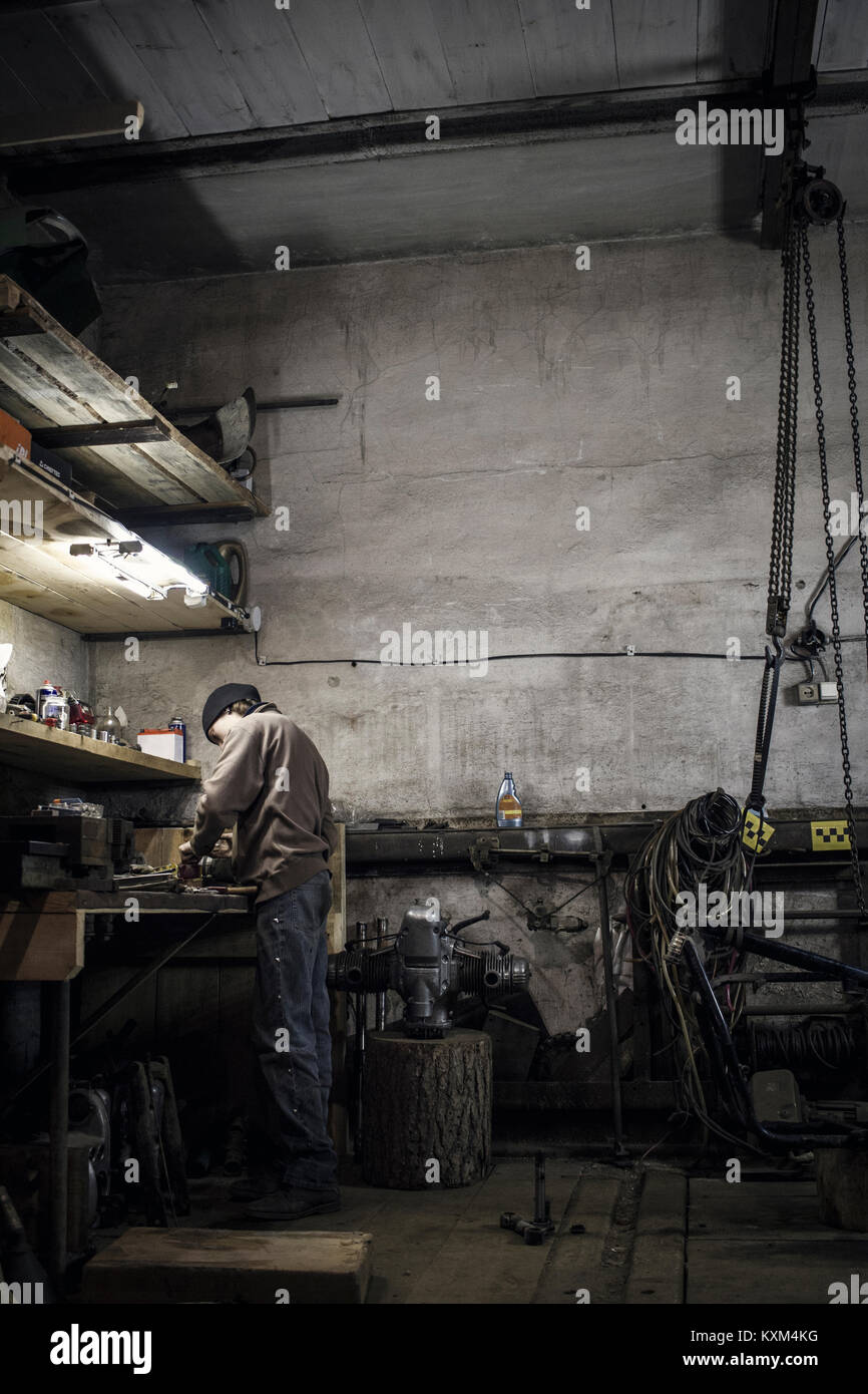 Mechanic working at bench with dismantled vintage motorcycle in workshop Stock Photo