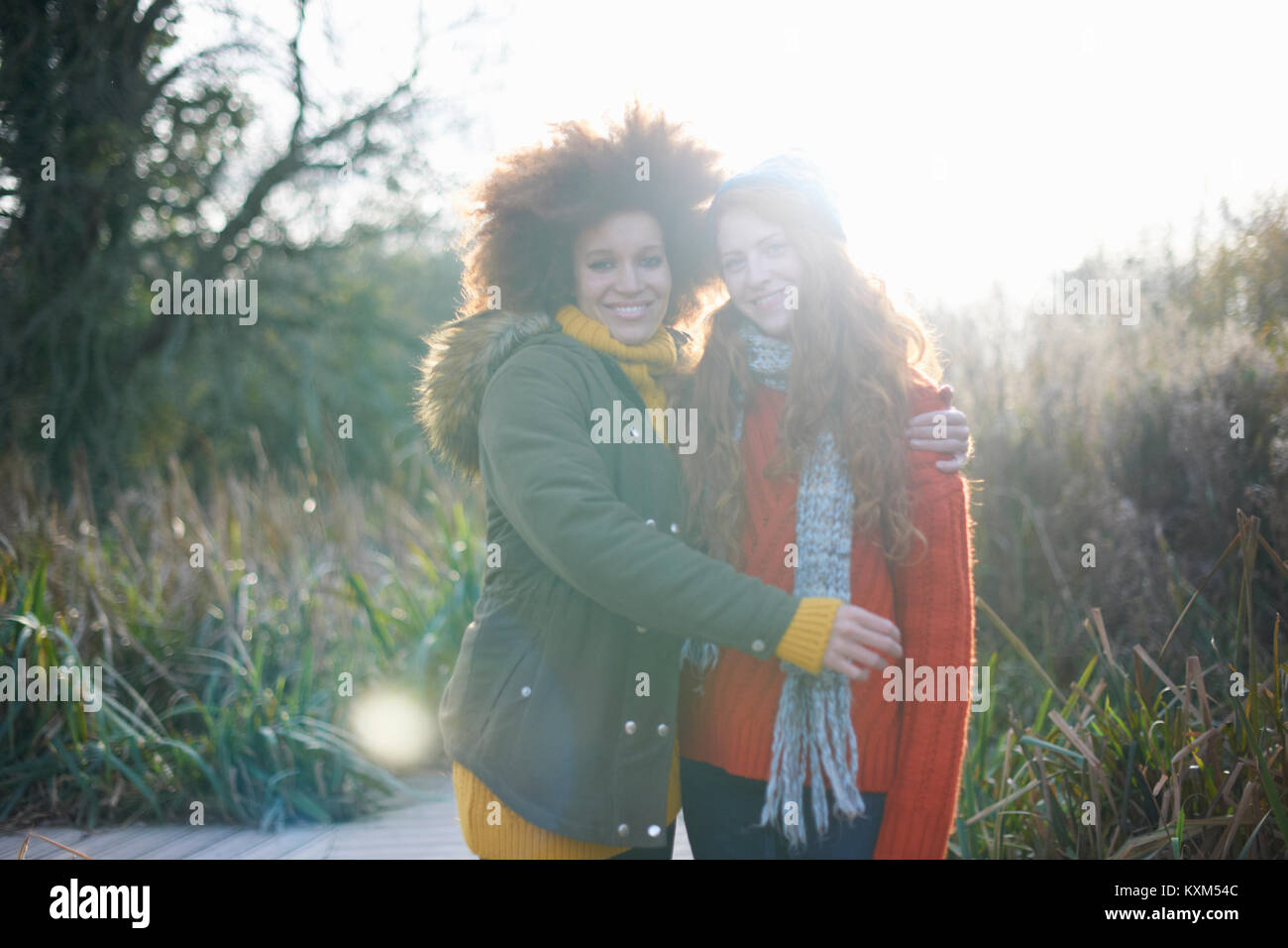 Friends hugging looking at camera smiling Stock Photo - Alamy