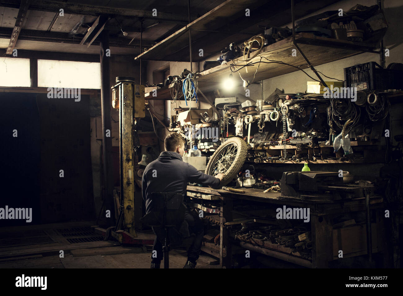 Mechanic repairing vintage motorcycle wheel at workshop bench Stock Photo