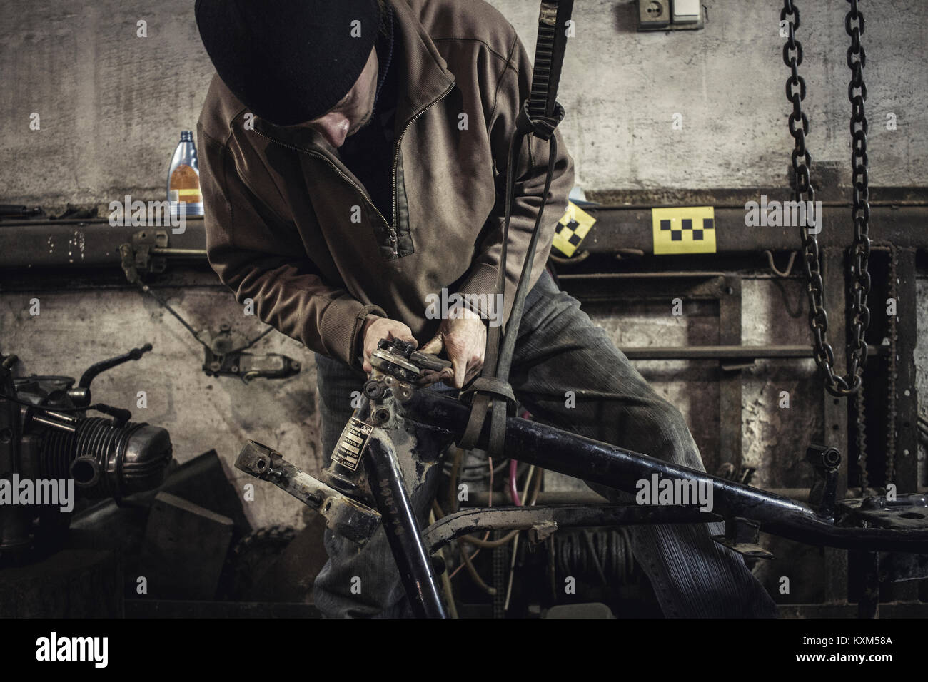 Mechanic repairing dismantled vintage motorcycle in workshop Stock Photo