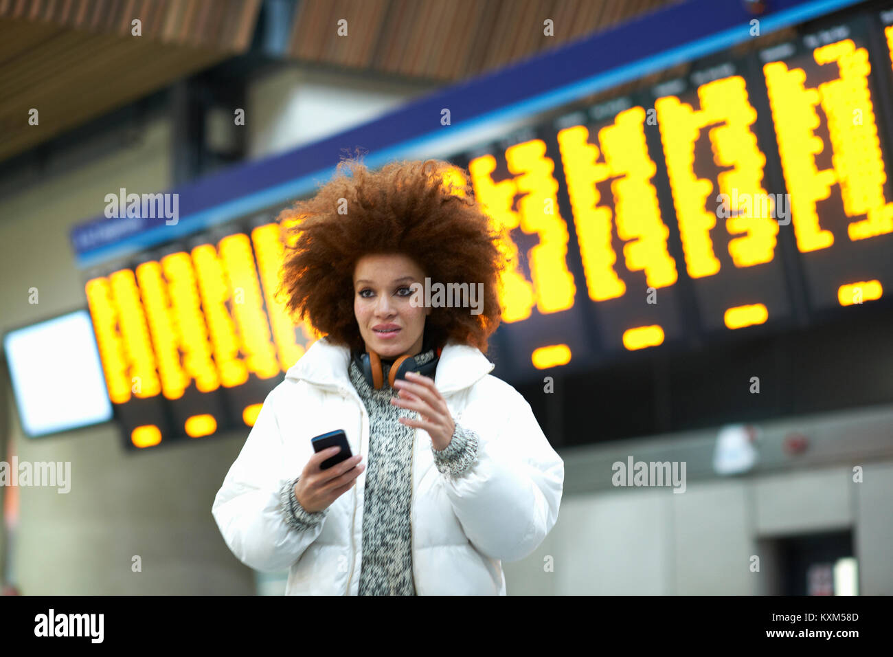 Young woman at train station,holding smartphone Stock Photo