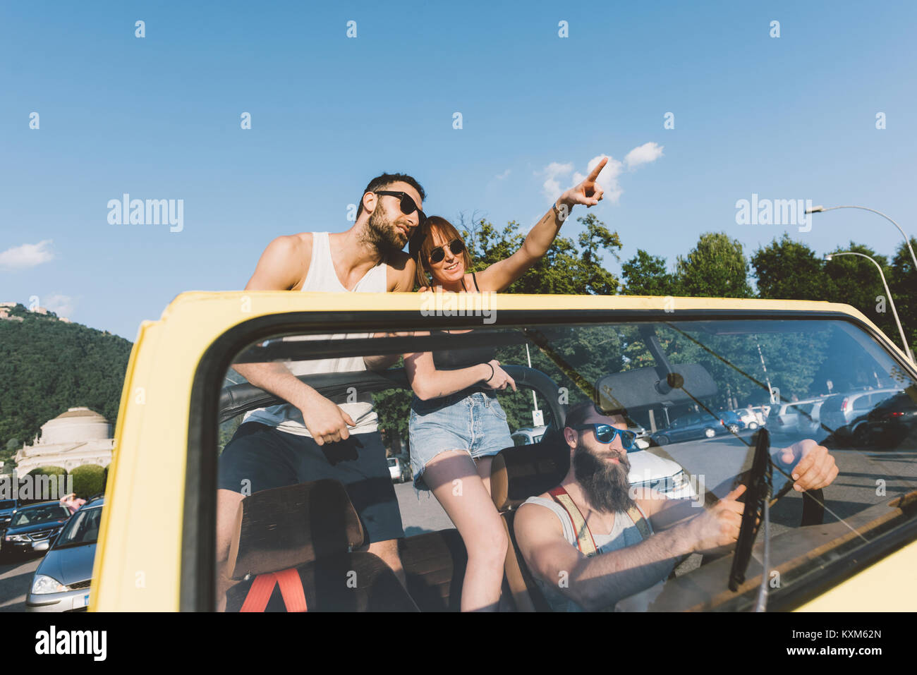 Three young adults driving and pointing on road trip in off road