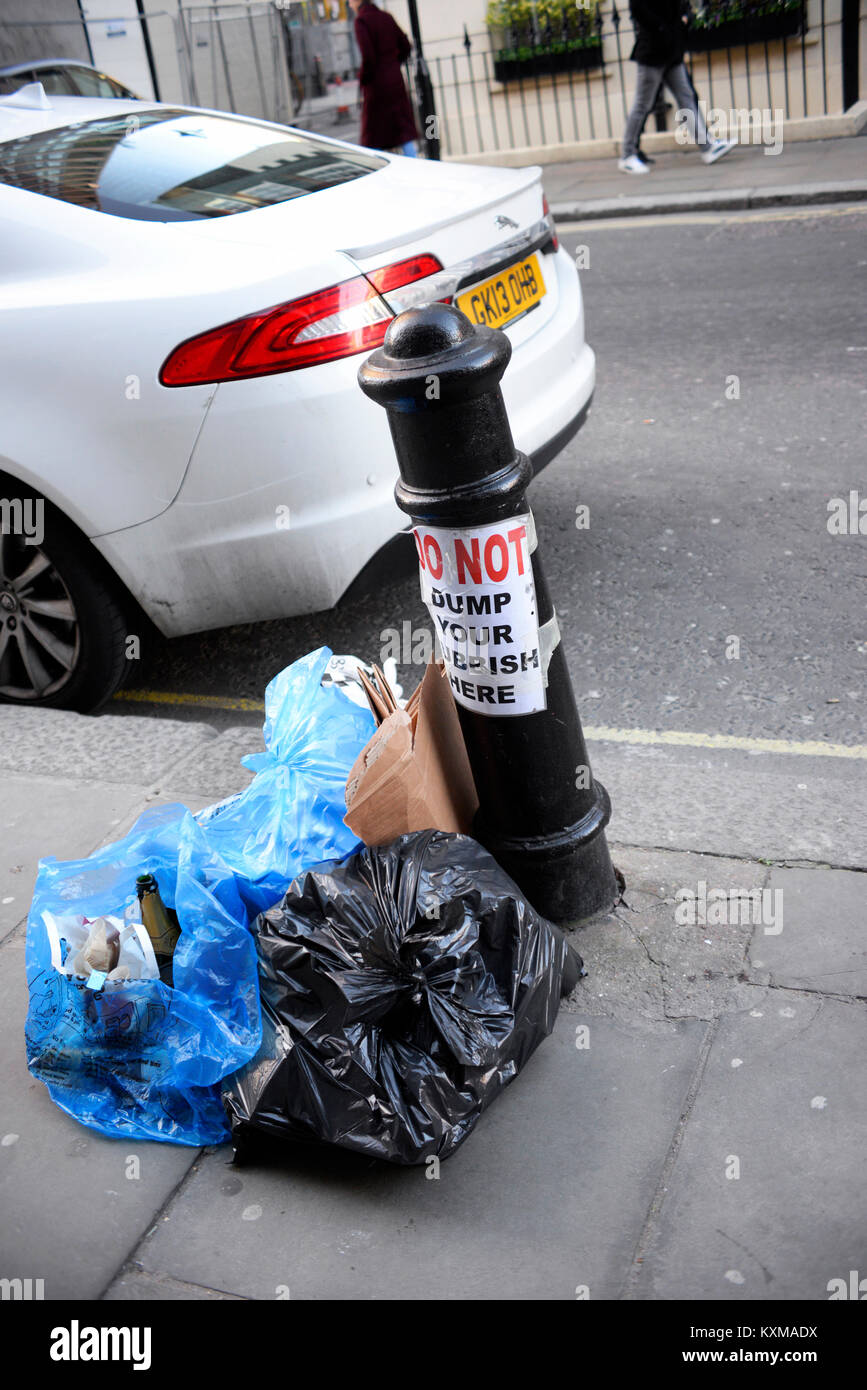 Pile of rubbish next to sign saying do not dump your rubbish here. London Stock Photo