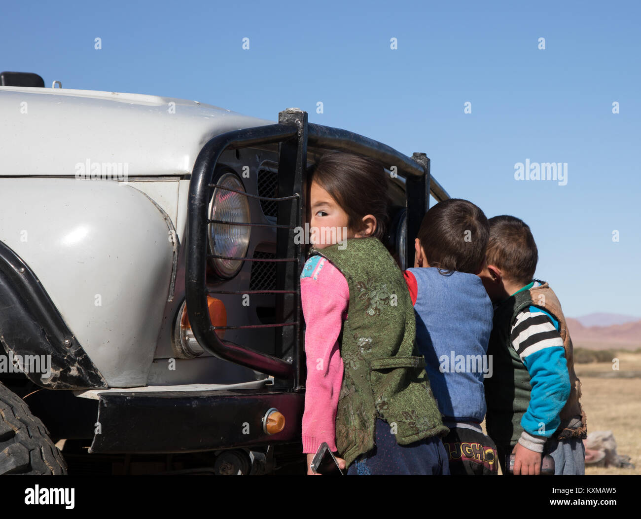 Country side rural kids playing with car little girl looking over her shoulder Mongolia Stock Photo