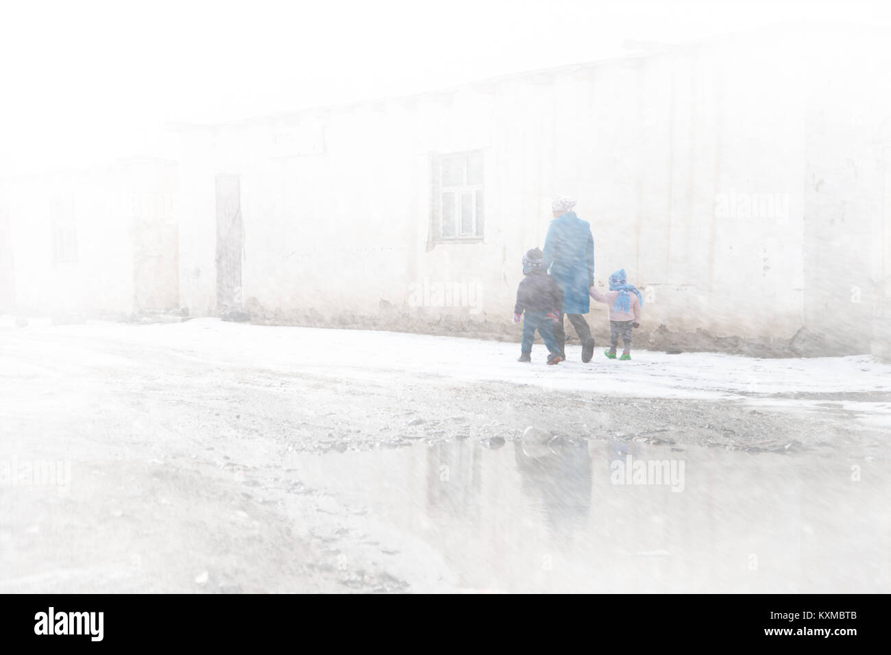 Country side rural mother and children kids walking blizzard snow foggy fog early morning Mongolia Stock Photo