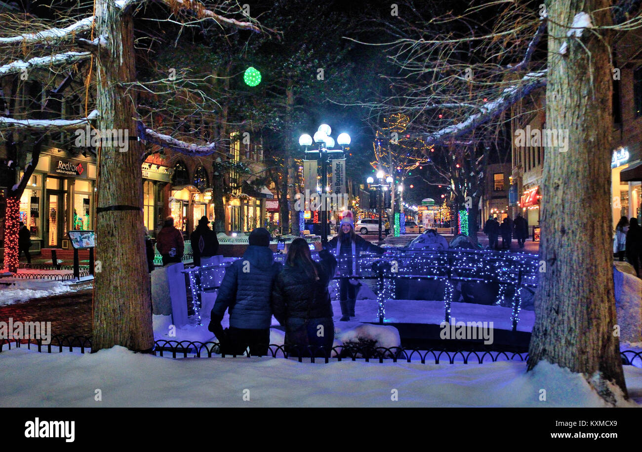 Adults taking photos of young girl amidst holiday lighting on Pearl Street Mal in Boulder Colorado during the Holiday Season. The walking bridge is at Stock Photo