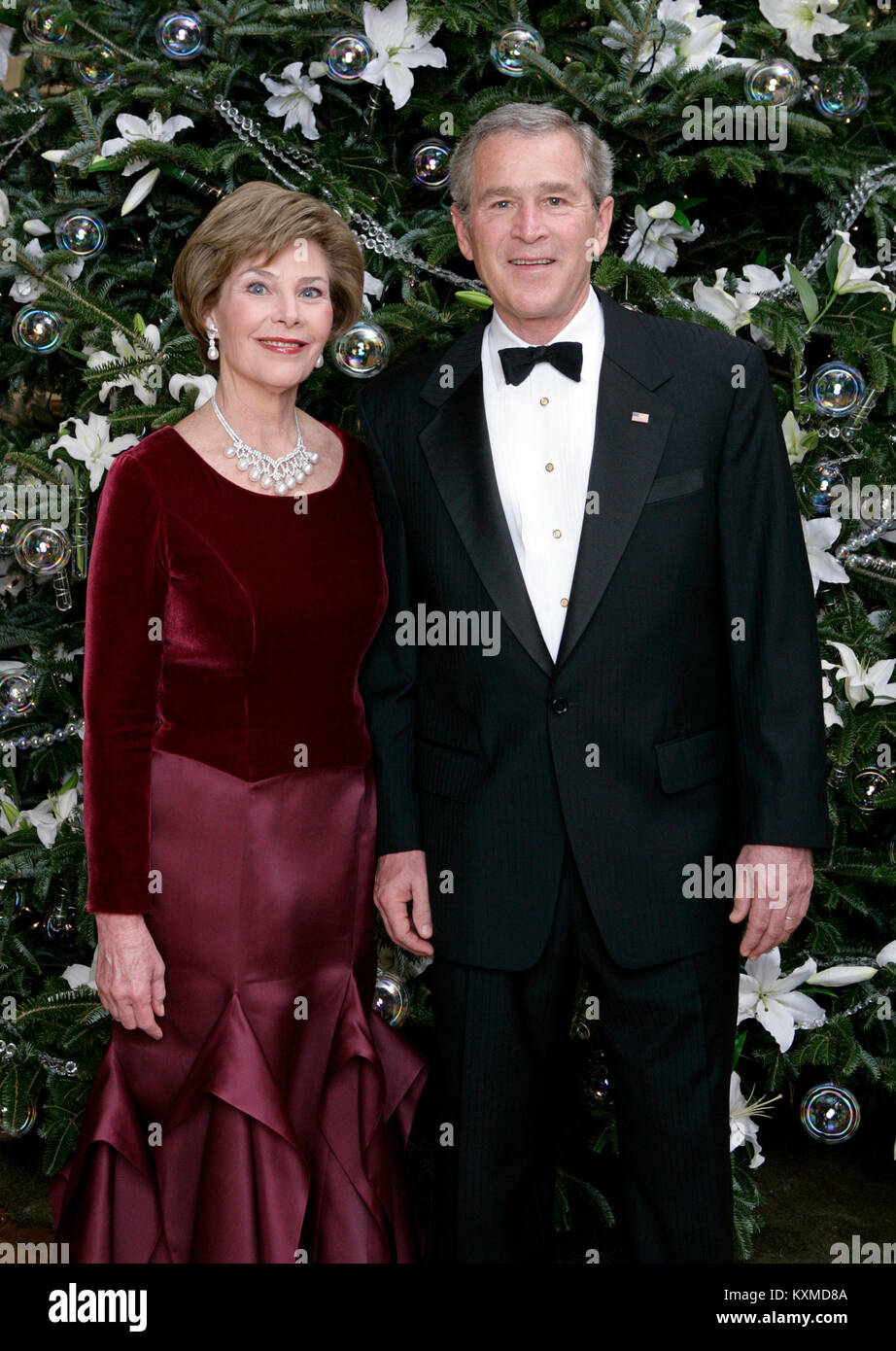 United States President George W. Bush and first lady Laura Bush pose for their Official Holiday Portrait near the White House Christmas tree in the Blue Room of the White House in Washington, D.C. on December 4, 2005.  In keeping with this year's theme, 'All Things Bright and Beautiful!' the Fraser fir is decorated with fresh white lilies. Mandatory Credit: Eric Draper - White House via CNP /MediaPunch Stock Photo