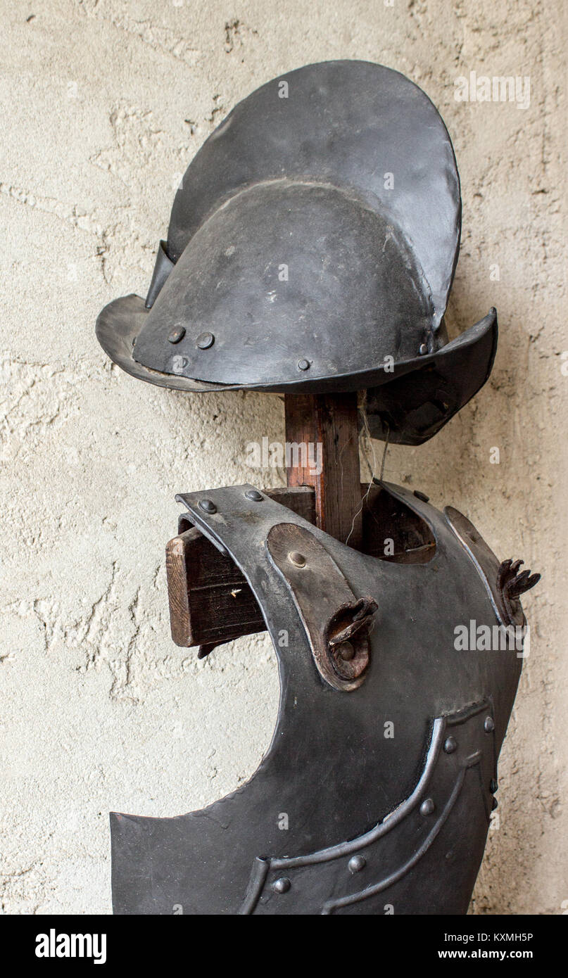 Historic armor and helmet on a wooden stake stands against the wall Stock Photo