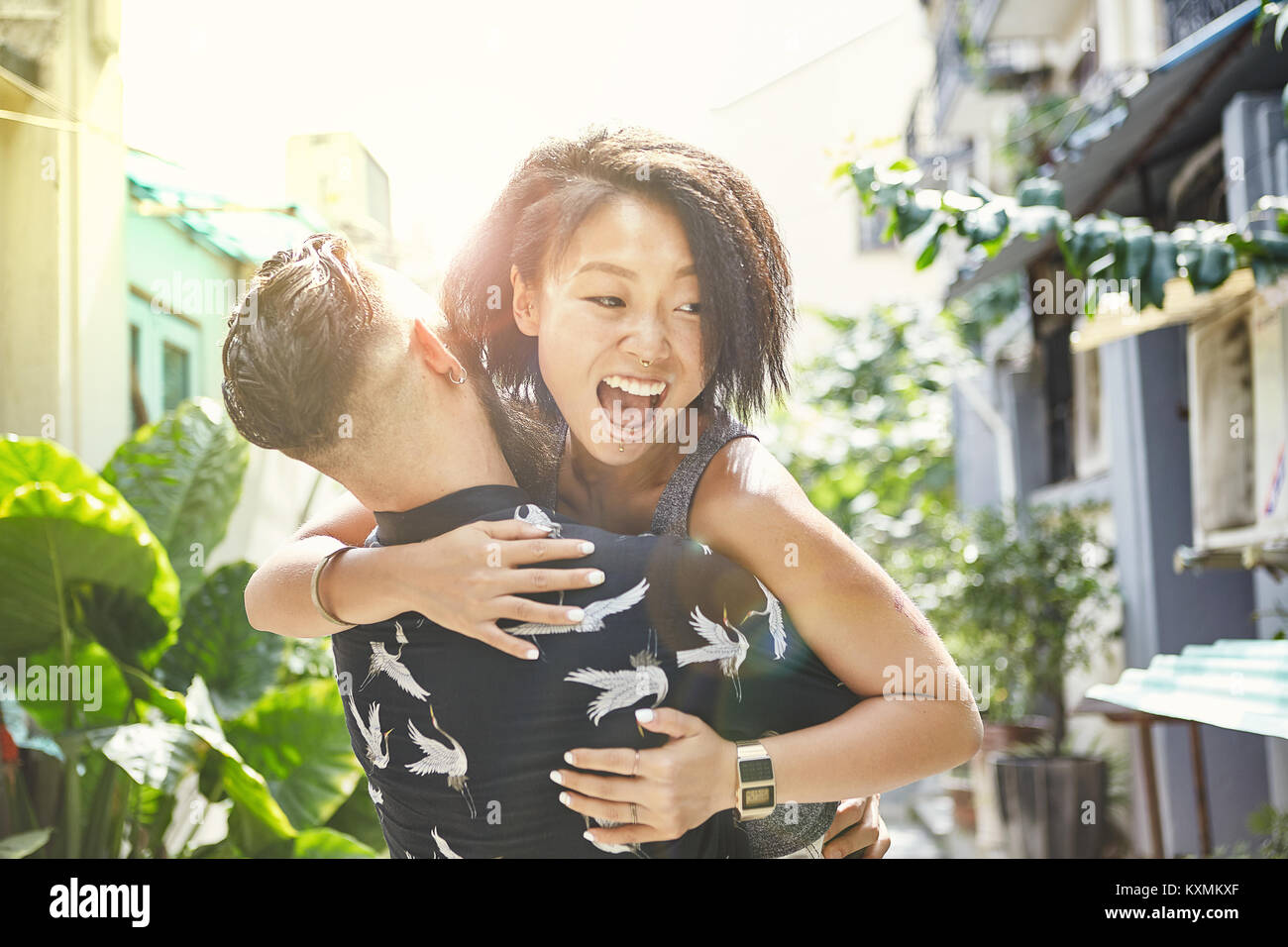 Young man lifting and hugging girlfriend in residential alleyway,Shanghai French Concession,Shanghai,China Stock Photo