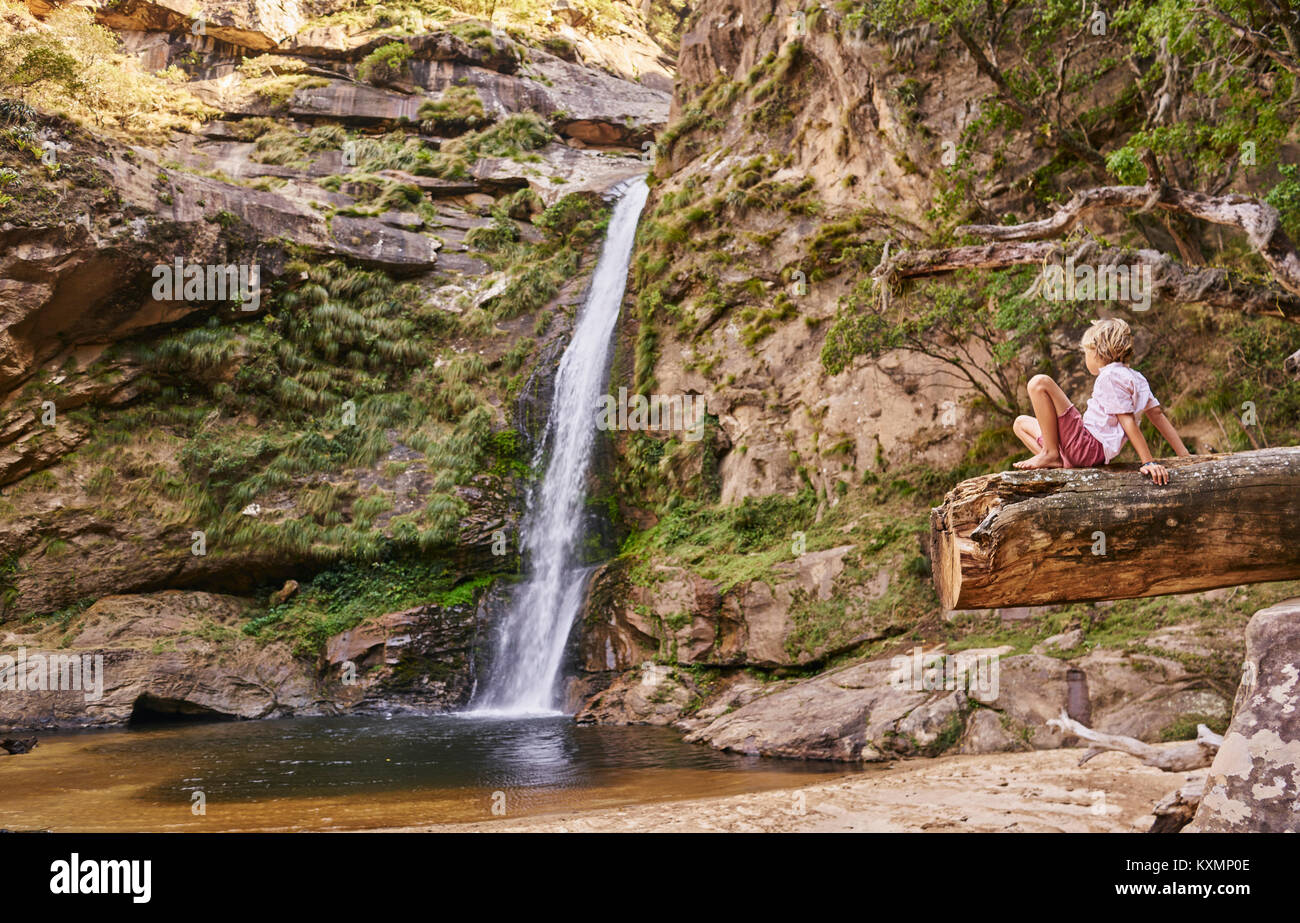 Boy sitting on log looking at waterfall,Samaipata,Santa Cruz,Bolivia,South America Stock Photo