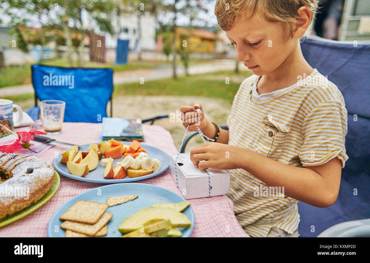 Boy at picnic table opening present,Florianopolis,Santa Catarina,Brazil,South America Stock Photo