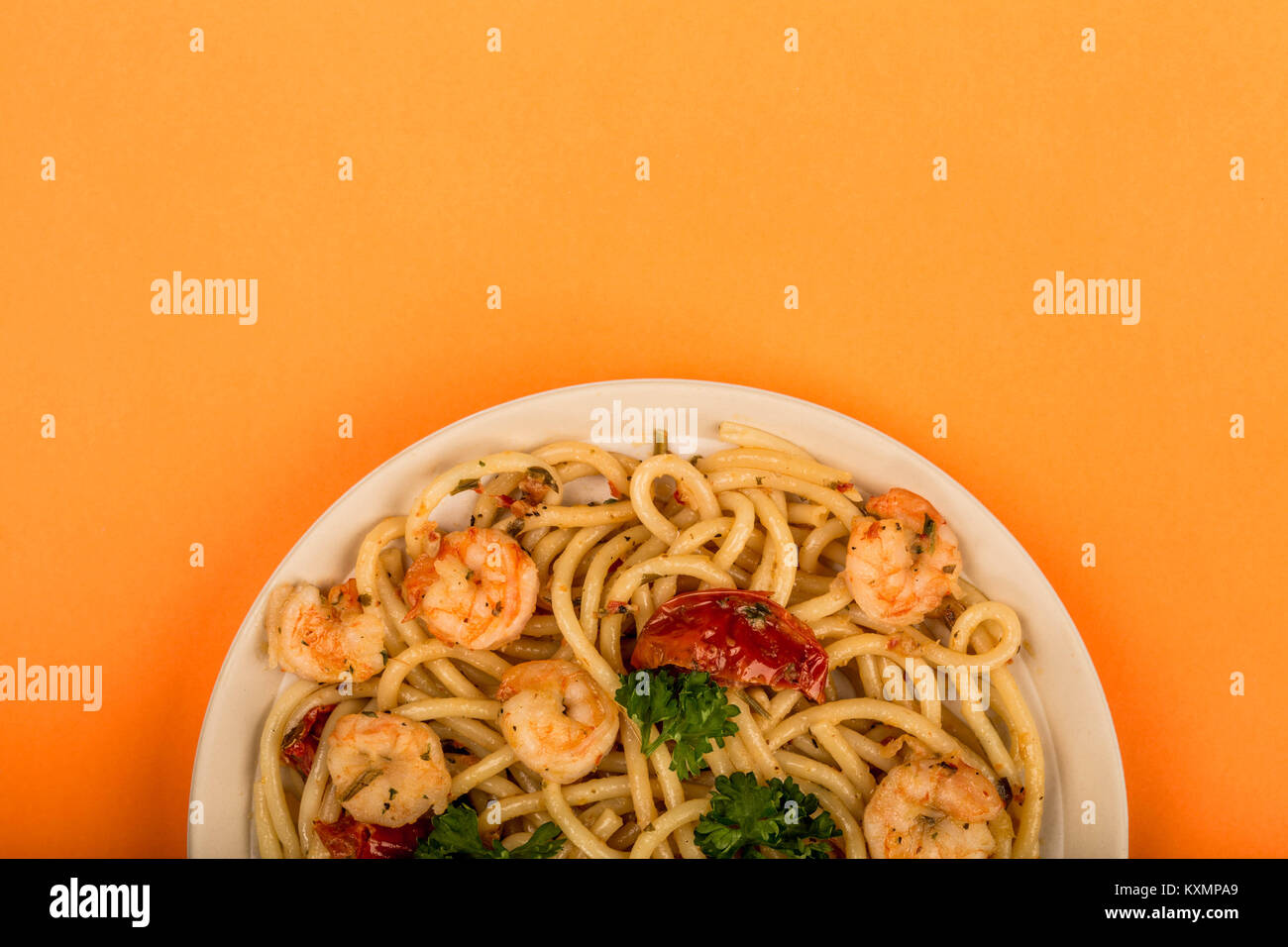 Italian Style Meal of King Prawn Bucatini Against An Orange Background Stock Photo