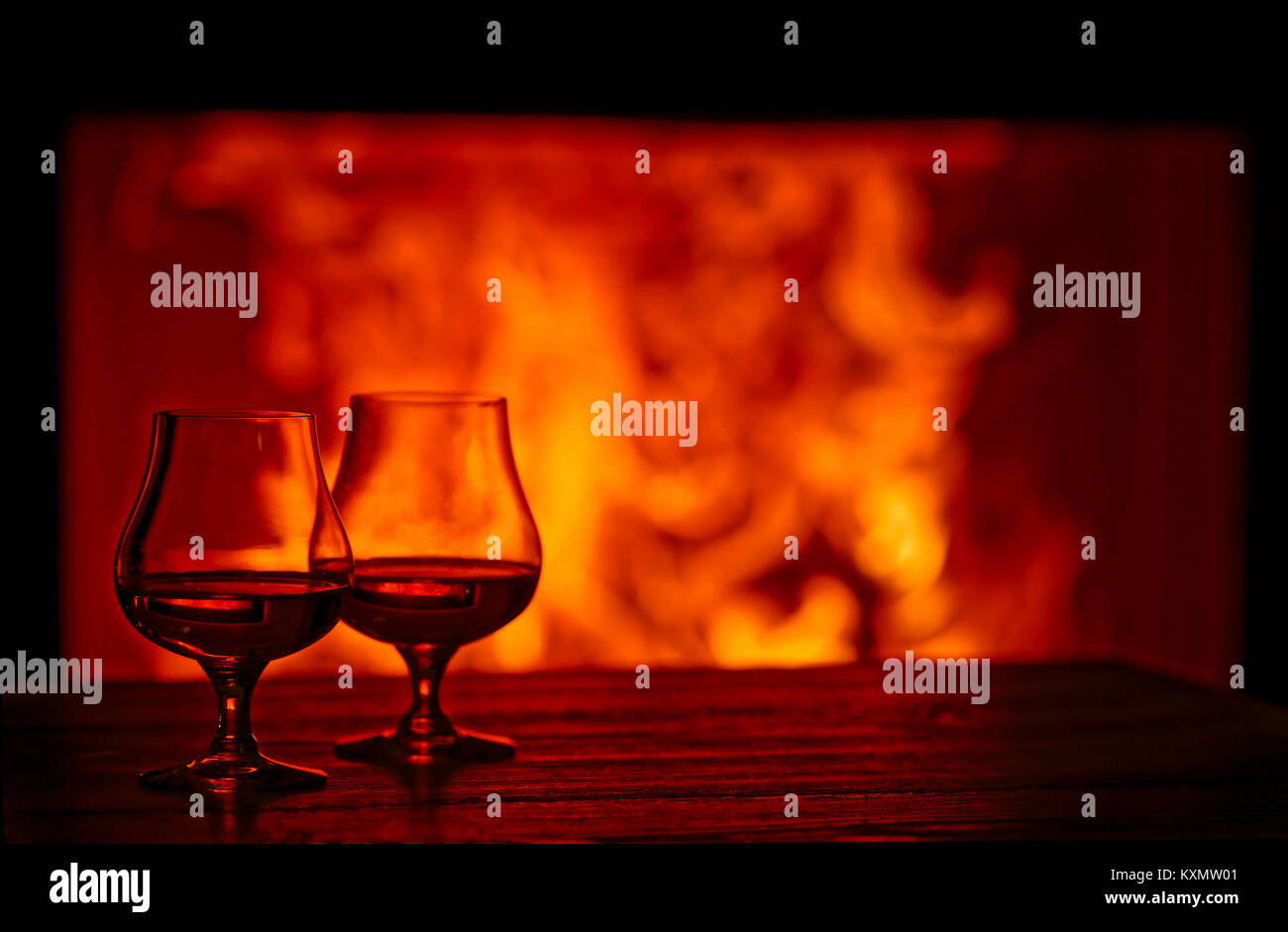 Two glasses of Brandy in front of a fireplace Stock Photo
