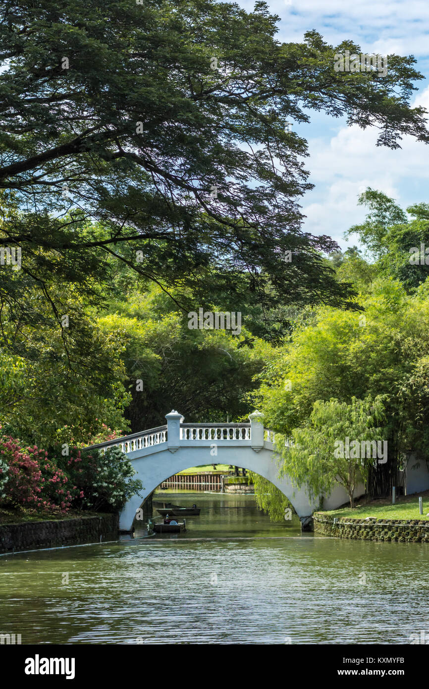 Chinese asian style concrete white footbridge over river in public oriental gardens on sunny day. Stock Photo