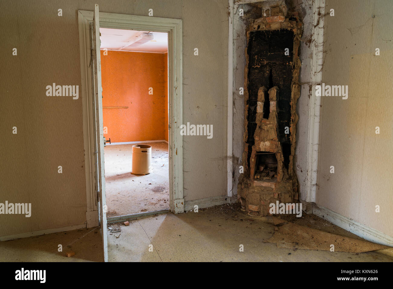 Dismantled tiled stove and open door inside a room in an abandoned house. Stock Photo