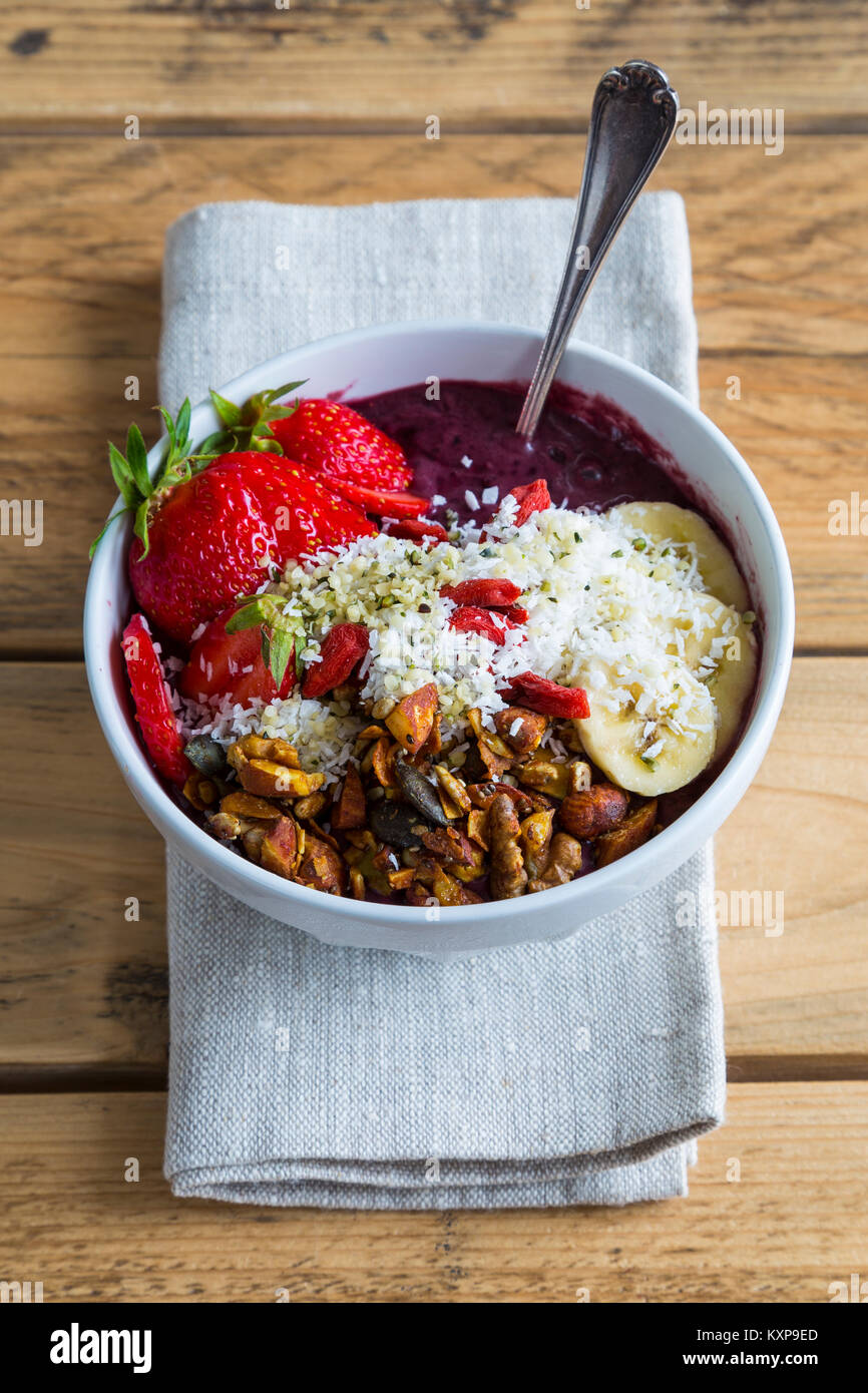 Acai bowl on napkin Bowl of acai purée with toppings of banana, strawberry, granola and seeds