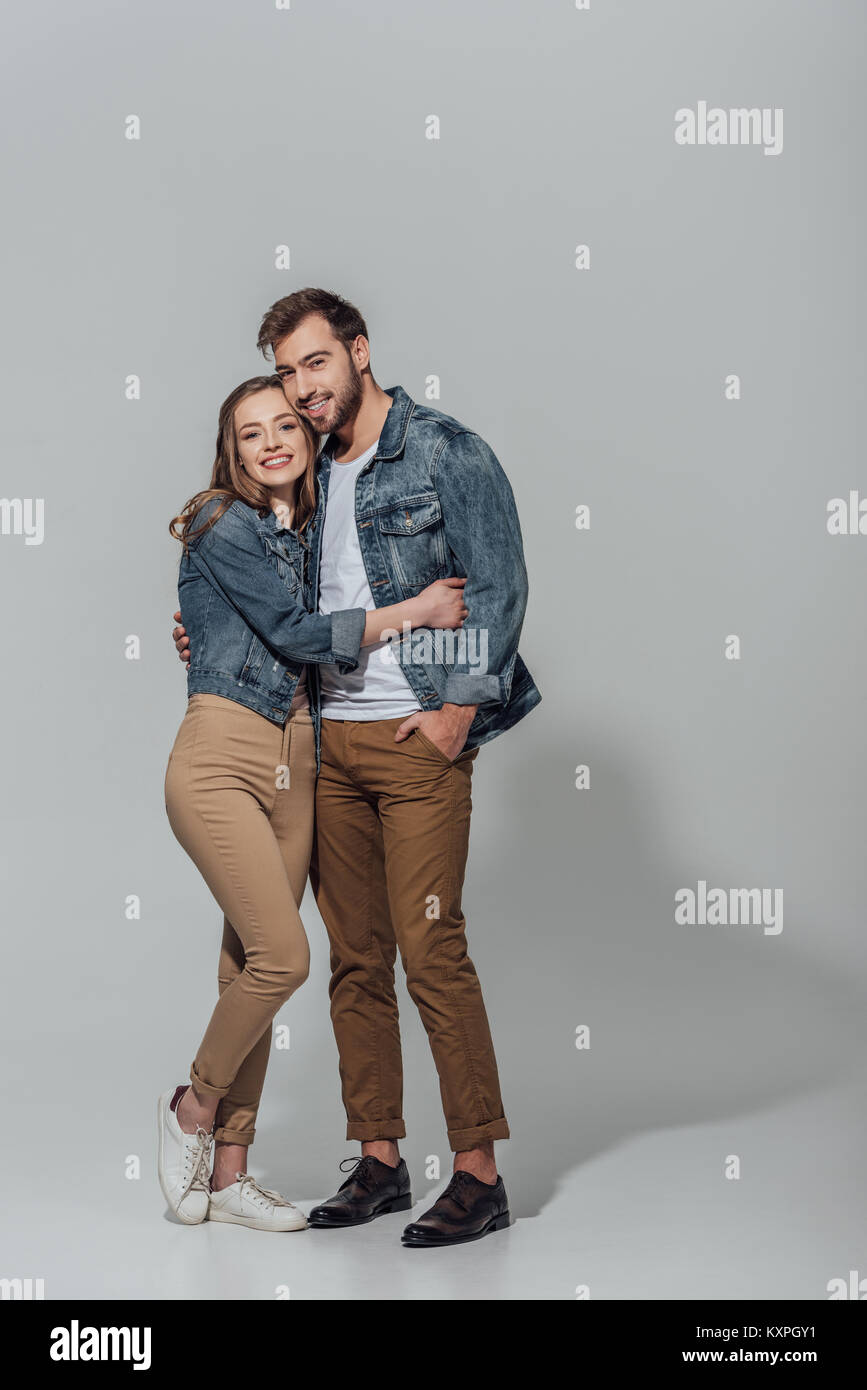 full length view of cheerful young couple hugging and smiling at camera ...