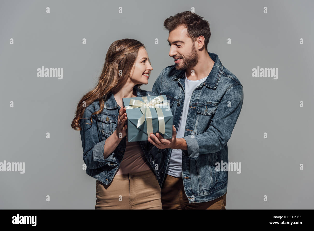 beautiful happy young couple holding gift box and smiling each other ...