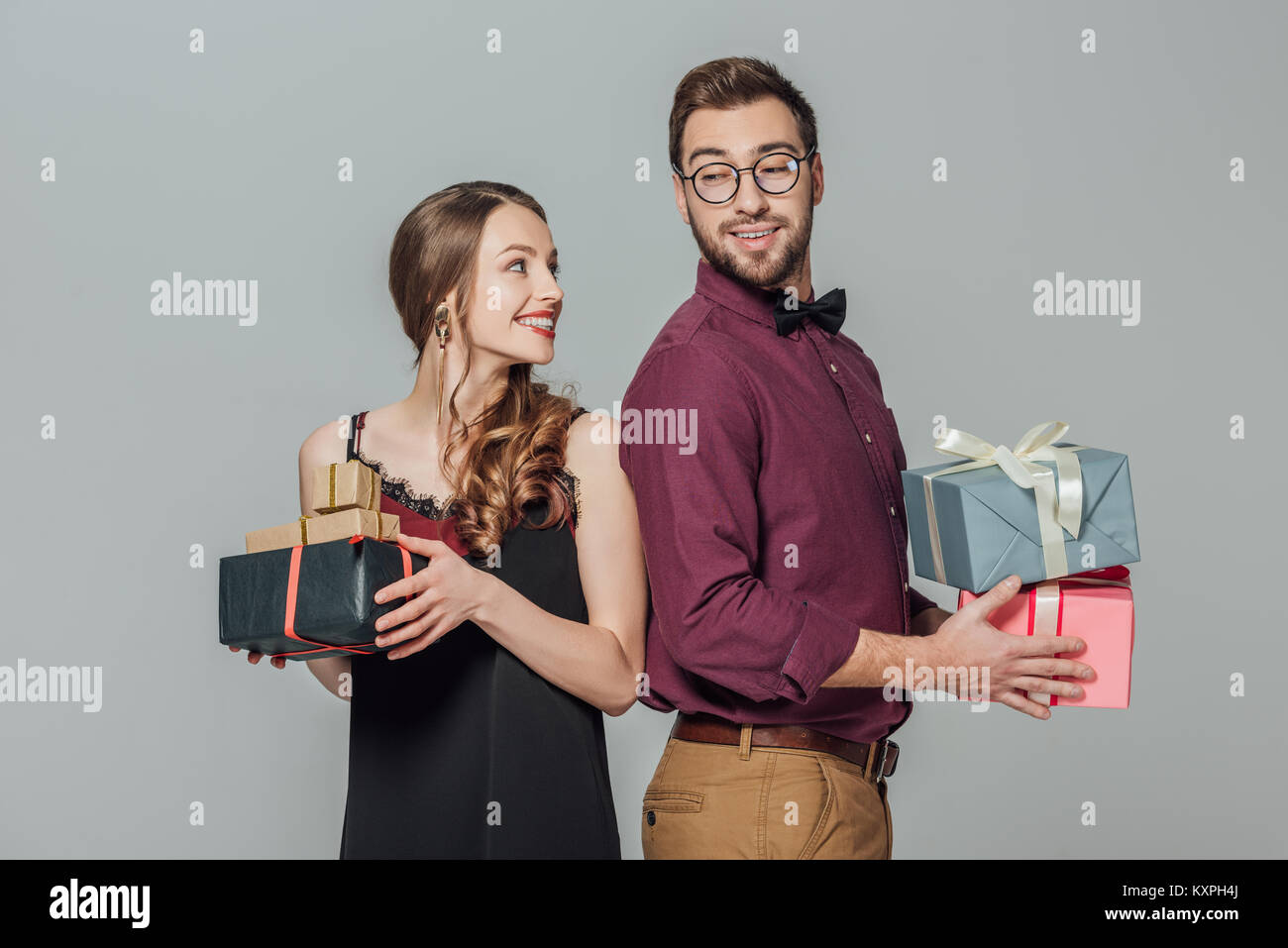 happy stylish young couple holding gift boxes and smiling each other ...