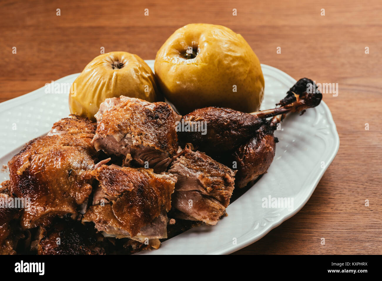 fried duck pieces laying on plate with marinated apples over wooden