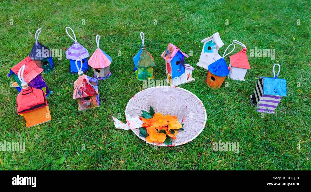 Lady's hat in front of fancy birdhouses on green grass with best mood Stock Photo