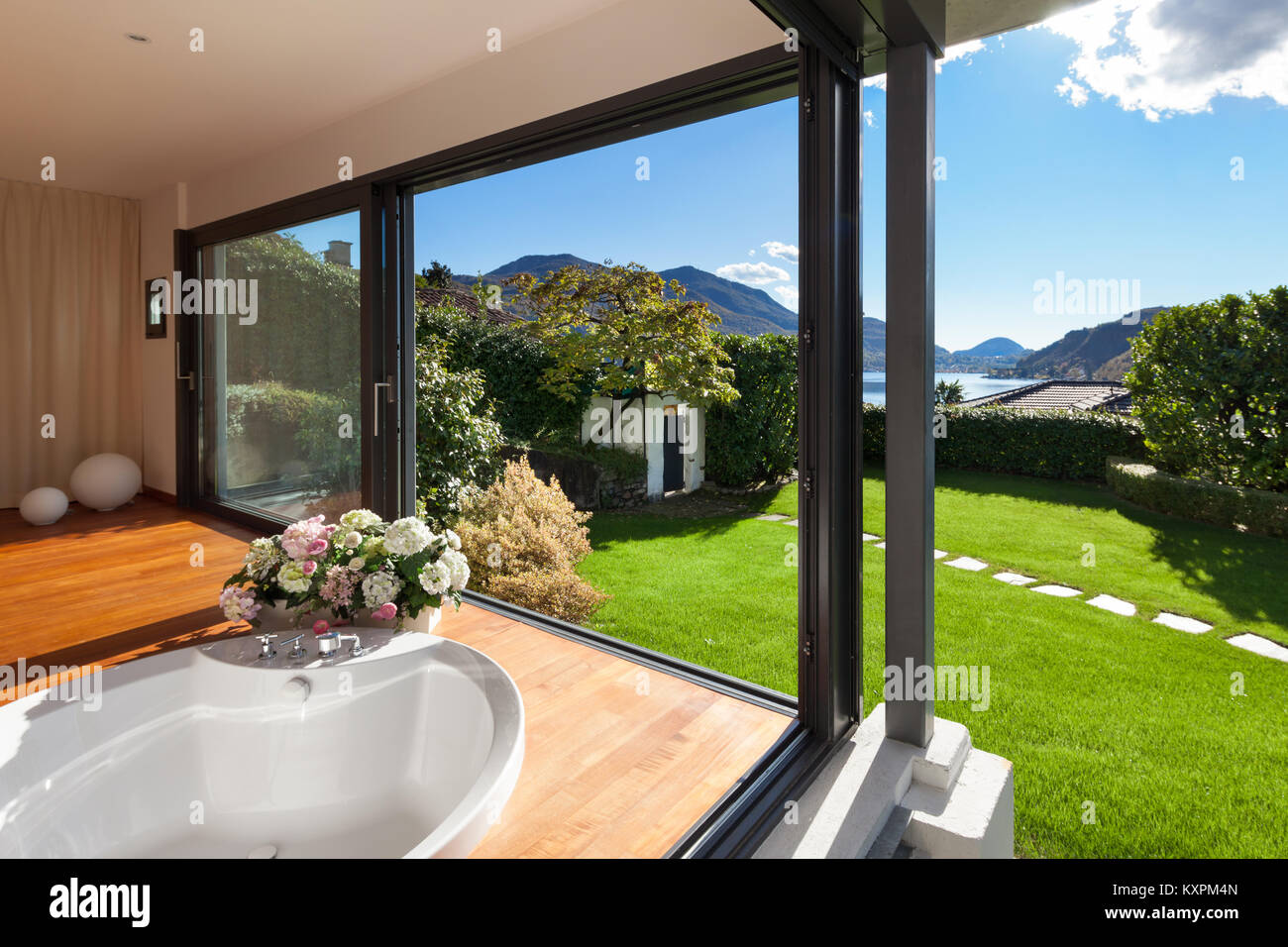 Comfortable bathroom with round bathtub, windows overlooking the garden Stock Photo