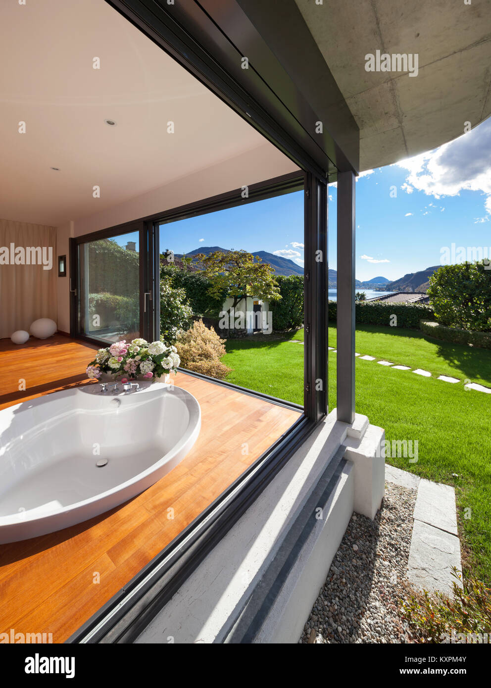 Comfortable bathroom with round bathtub, windows overlooking the garden Stock Photo