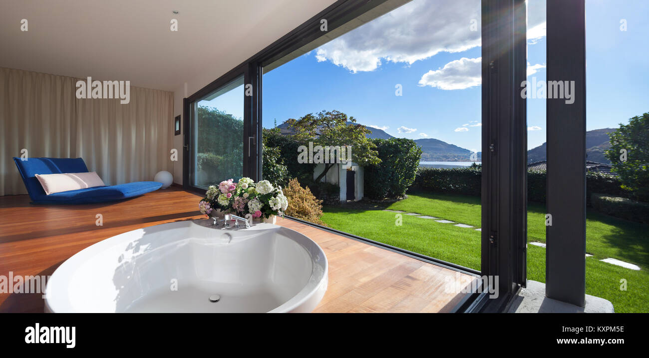 Comfortable bathroom with round bathtub, windows overlooking the garden Stock Photo