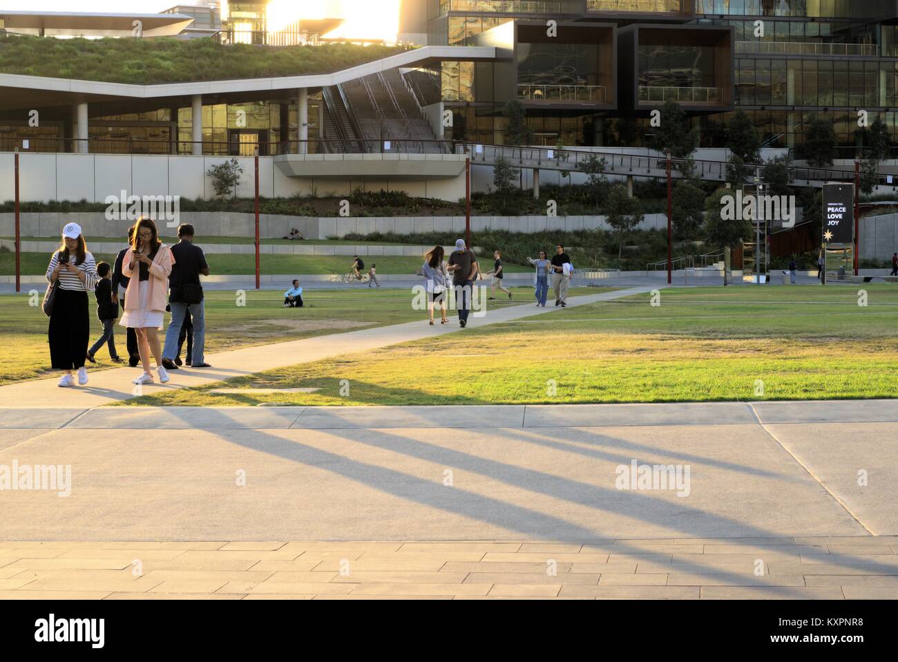 Sydney Outdoors golden hour. Busy people walking pedestrian boulevard outside International Convention Centre or ICC Sydney Darling Harbour Australia Stock Photo