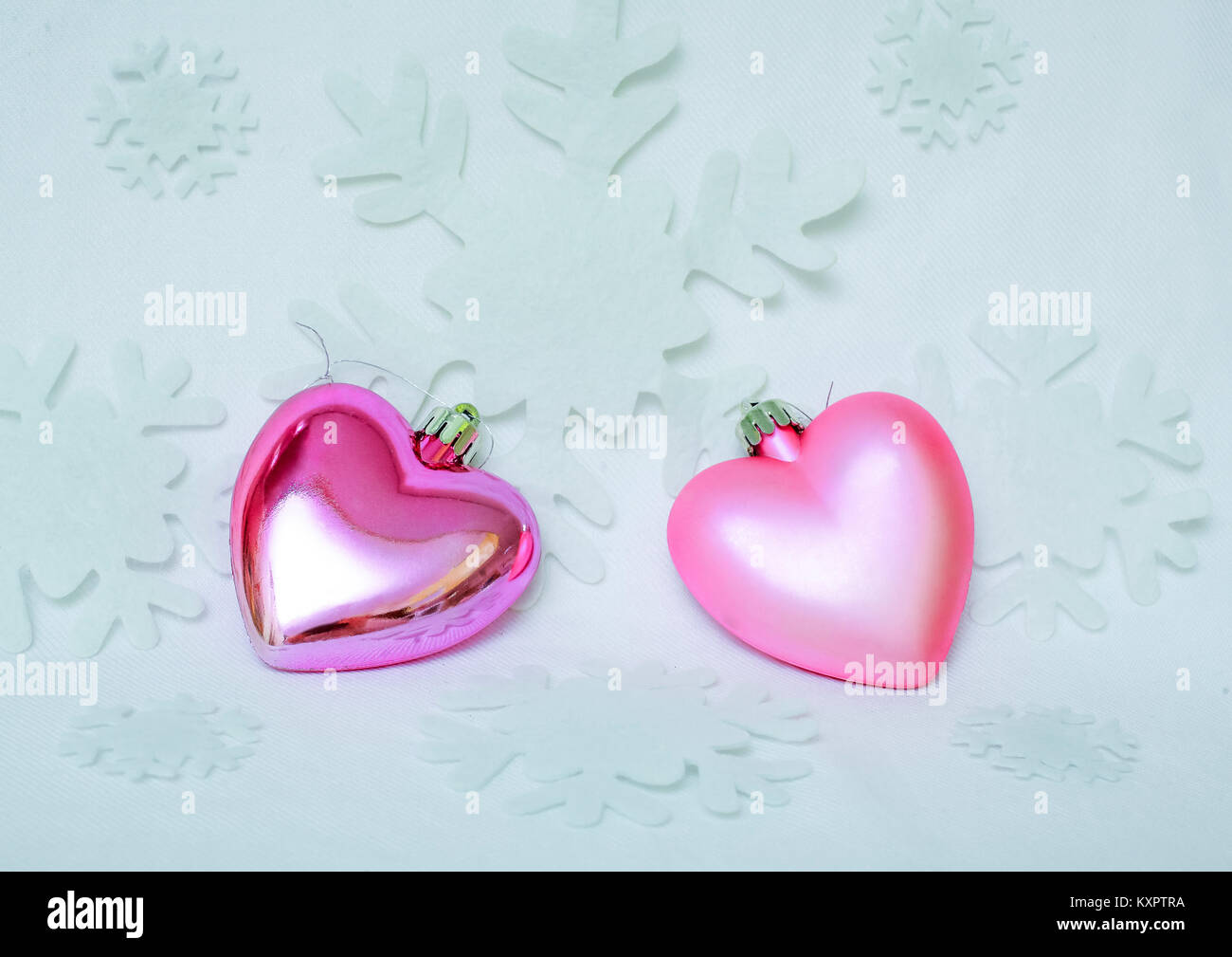 On white background of snowflakes on two sparkly pink heart - symbol of love and fidelity. Stock Photo