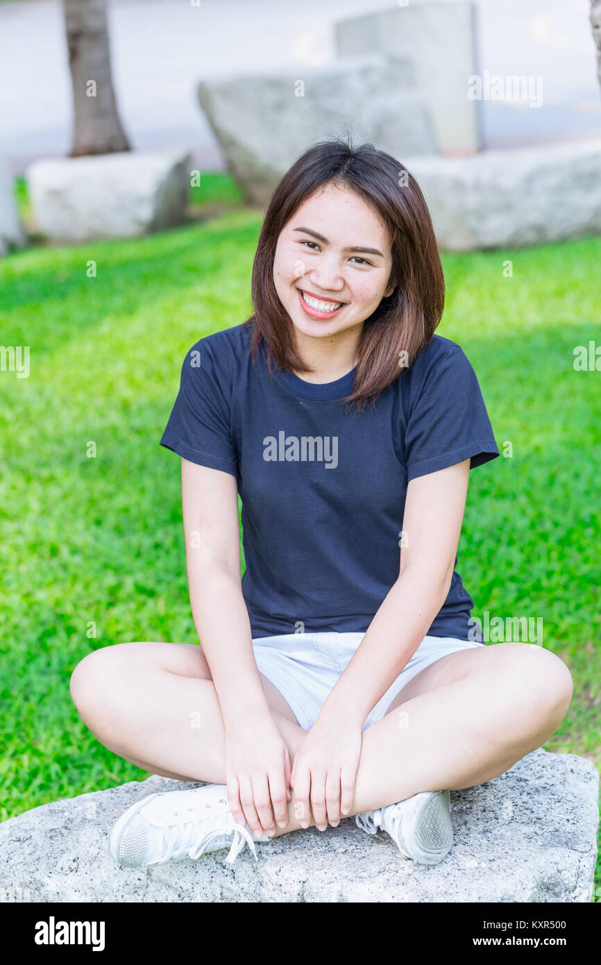 Single asian women teen cute short hair friendly smiley in the green park relax and smile. Stock Photo
