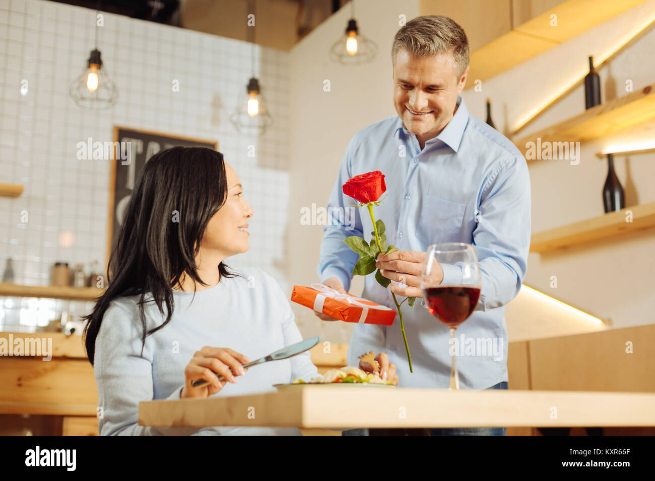 Romantic man giving rose and present to his woman Stock Photo