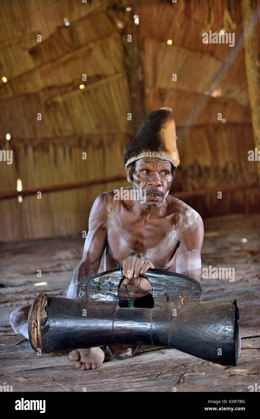 Asmat with a drum. Man from the tribe of Asmat with traditional face painting beats the drum. May 23, 2016 Stock Photo