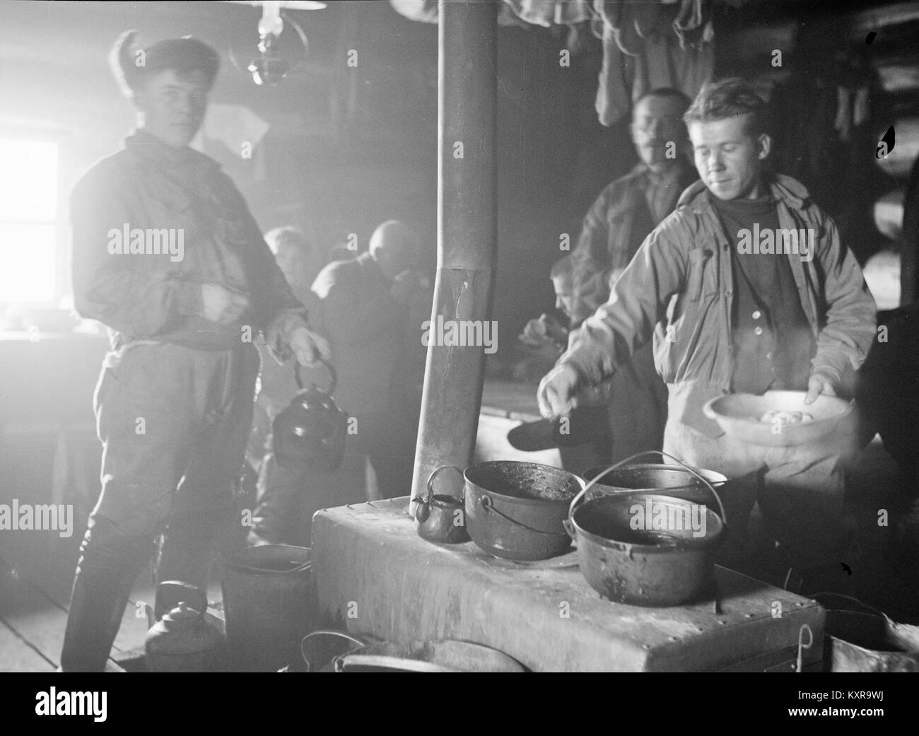 Male foresters cooking on stove in cabin, Finland 1930s Stock Photo