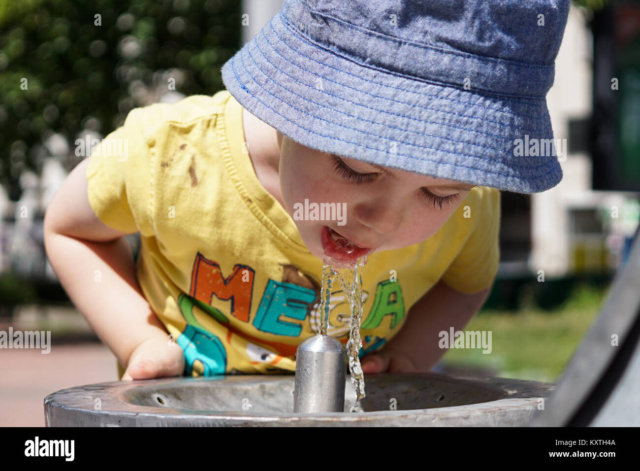 A thirsty boy drinking water from the fountain. Stock Photo