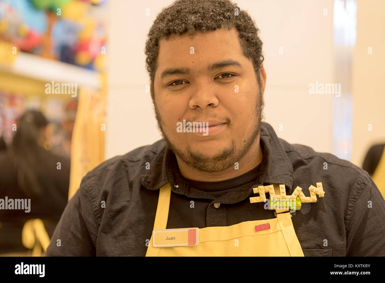 A clerk at the Lego store on FIfth Ave. in Manhattan, New York City. wearing a nametag made out of Legos. Stock Photo