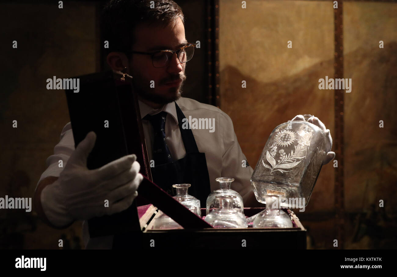 A gallery technician handles decanters included in Lord Nelson's Grog Chest, dating from circa 1800, part of the Of Royal and Noble Descent sale at Sotheby's in London on 17th January. Stock Photo