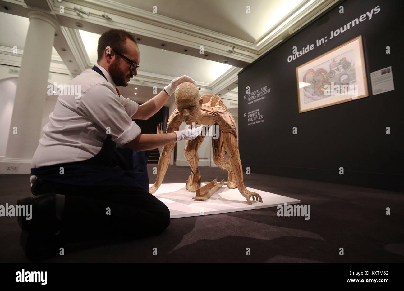 A gallery technician adjusts a work by James Lake titled Running Figure during a photo call for Sotheby's Outsider Art exhibition celebrating the work of the Outside In charity at Sotheby's in London. Stock Photo