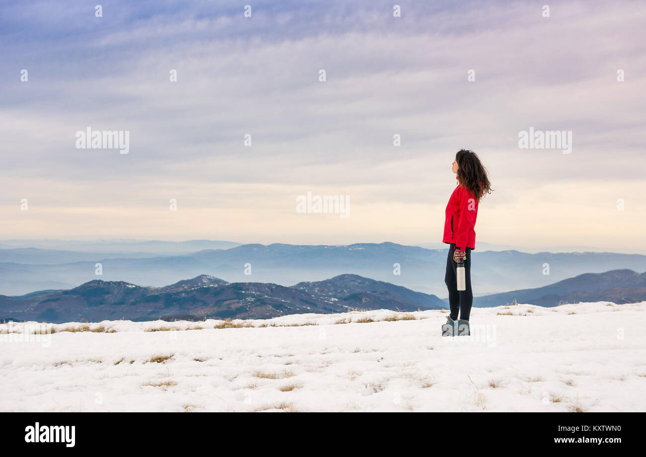 Female hiker admiring winter scenery on a mountaintop alone Stock Photo