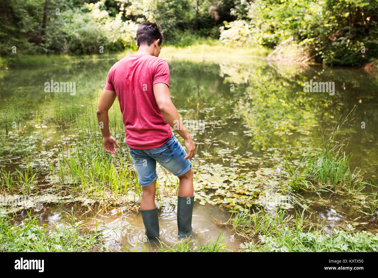 Teenage boy in rubber boots standing in lake Stock Photo Alamy